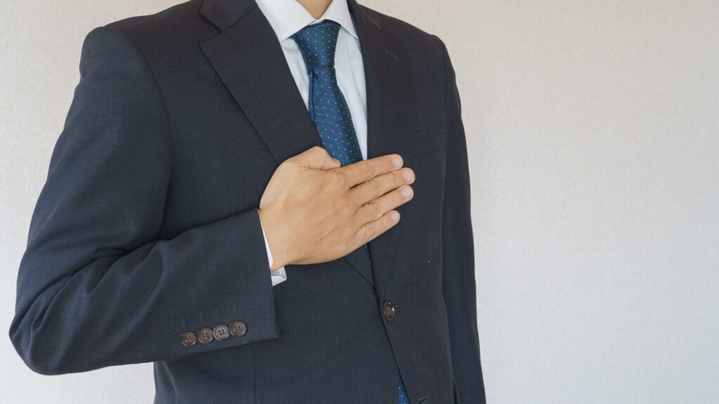 胸に手をあてて、安心を示す上司