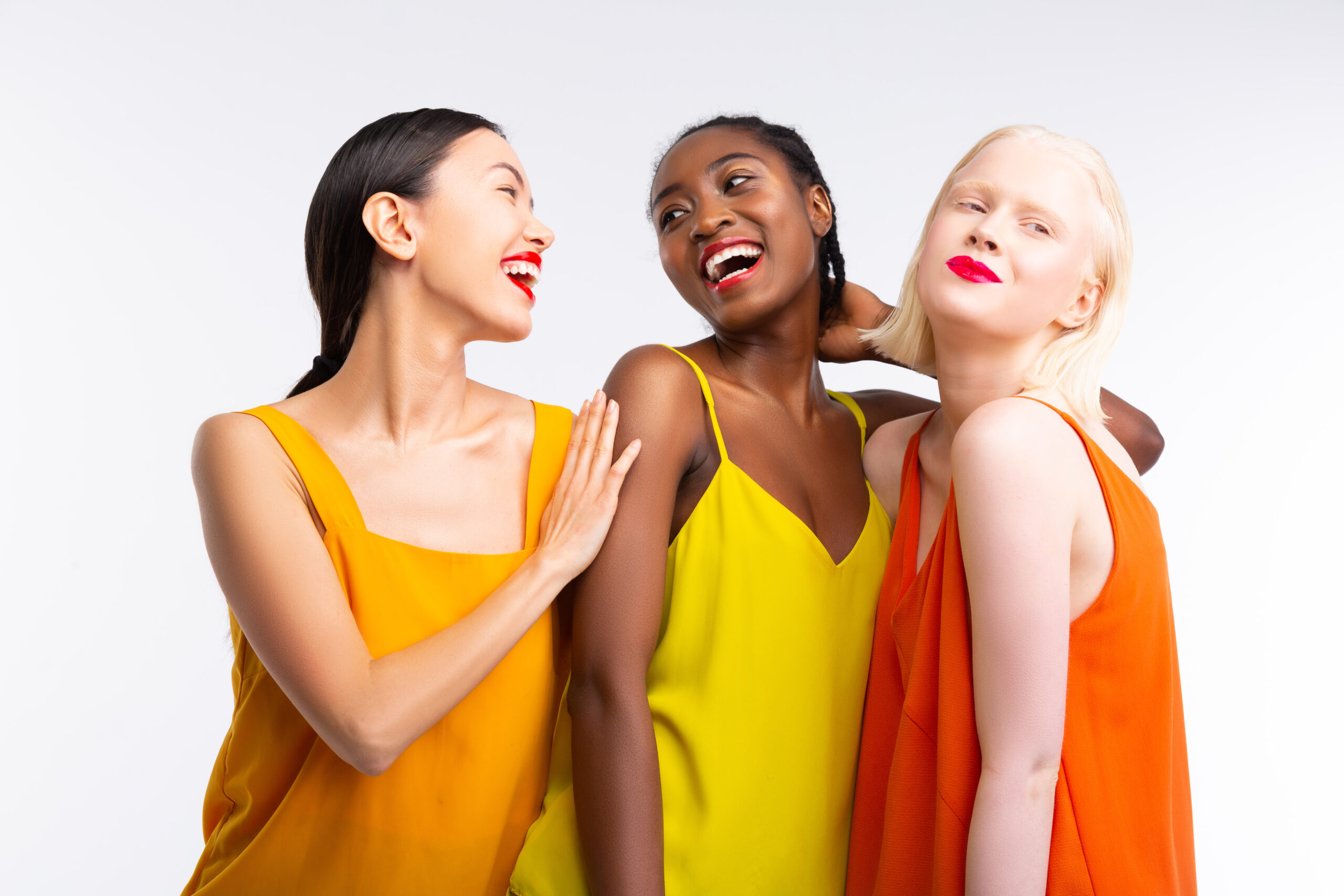 Colorful clothes. Beaming cheerful women with different skin color wearing bright colorful clothes